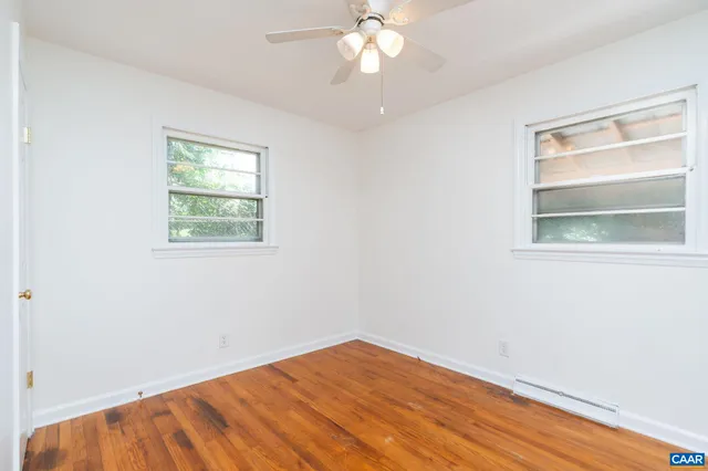 a view of empty room with wooden floor and fan