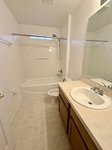 a bathroom with a granite countertop sink a toilet and shower