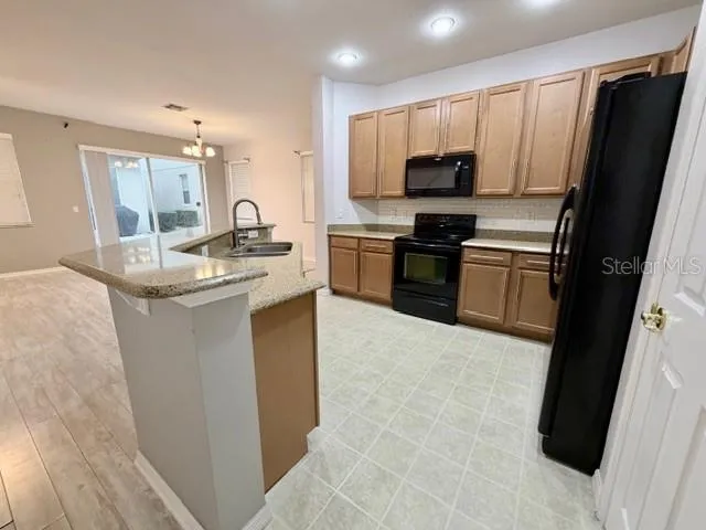 a kitchen with kitchen island granite countertop stainless steel appliances stove microwave refrigerator and cabinets