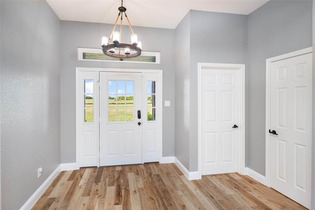1019 Vaughan Lane Tioga, TX 76271 - Photo 13 of 40 Foyer featuring a wood-finish flooring, white paneled doors, and a decorative chandelier