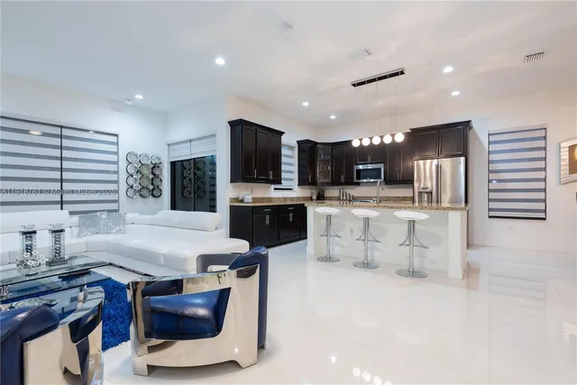 a kitchen with stainless steel appliances kitchen island granite countertop a stove top oven a sink a dining table and chairs