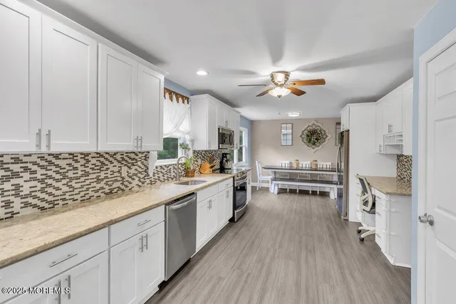 a kitchen with stainless steel appliances a stove a sink and white cabinets with wooden floor