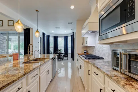 a kitchen with stainless steel appliances granite countertop a sink a stove and a wooden floor