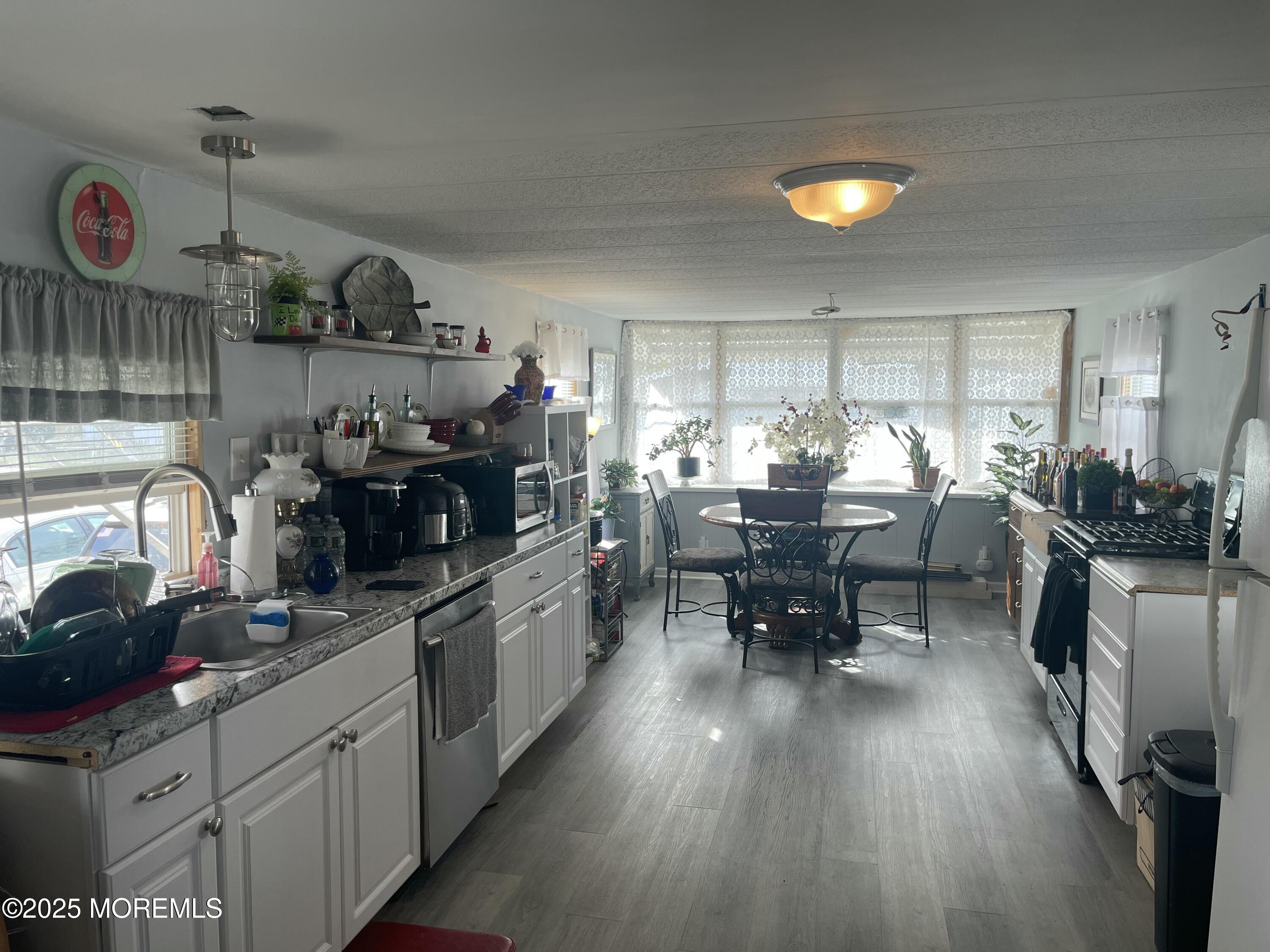 a kitchen with stainless steel appliances granite countertop dining table chairs and white cabinets