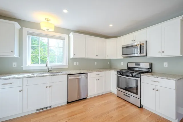 a kitchen with granite countertop white cabinets white stainless steel appliances and a sink