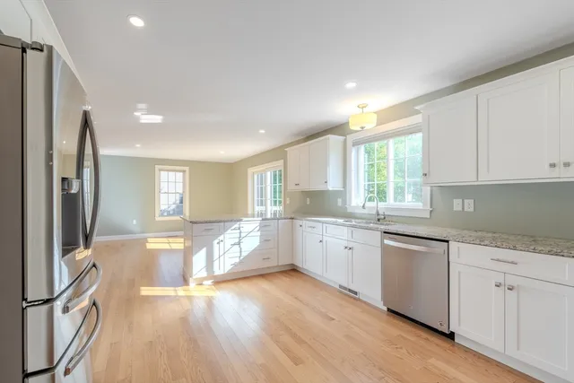 a large kitchen with granite countertop a large counter top space a sink stainless steel appliances and cabinets