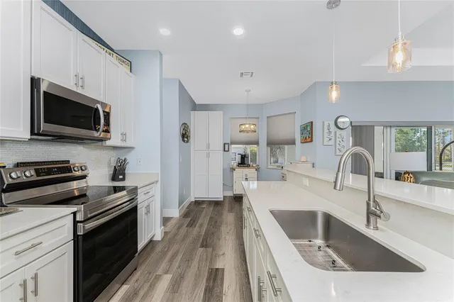 a large kitchen with white cabinets and stainless steel appliances