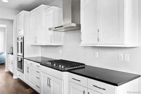 a kitchen with granite countertop white cabinets and white appliances