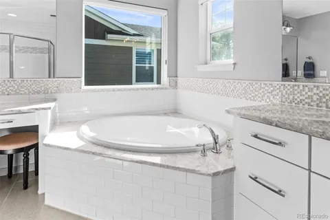 a bathroom with a granite countertop sink a mirror and a bathtub