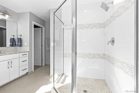 a bathroom with a granite countertop sink a mirror and shower