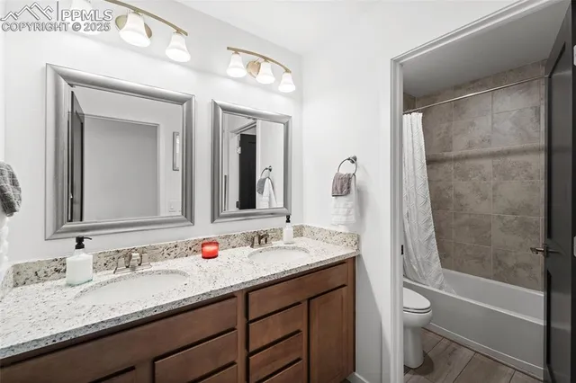 a bathroom with a granite countertop sink toilet mirror and shower