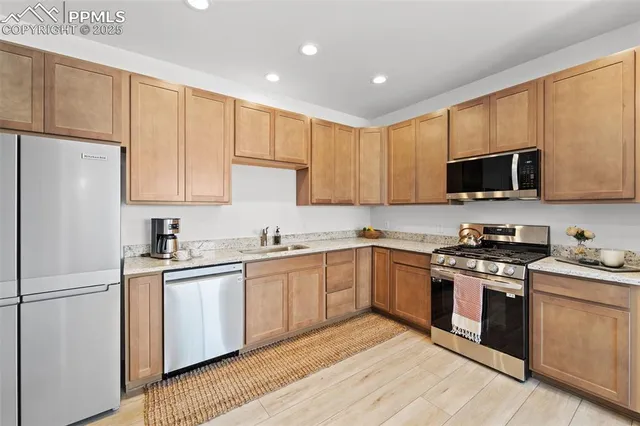 a kitchen with stainless steel appliances granite countertop a stove top oven a refrigerator a sink and dishwasher with wooden floor