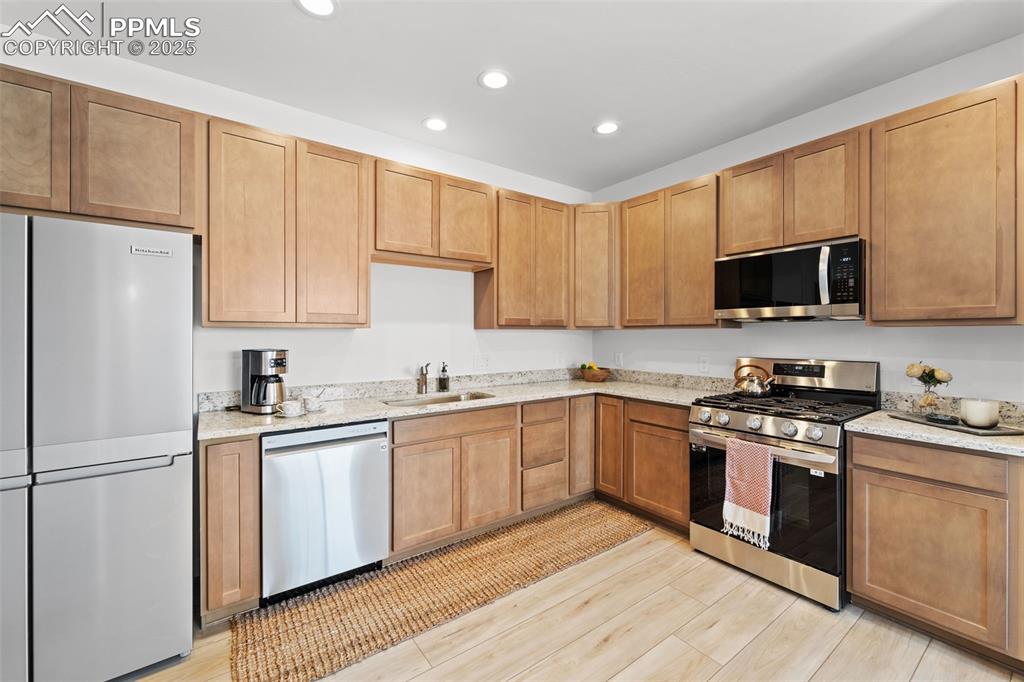 1920 Erin Loop Colorado Springs, CO 80918 - Photo 6 of 26 a kitchen with stainless steel appliances granite countertop a stove top oven a refrigerator a sink and dishwasher with wooden floor
