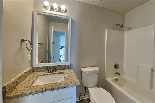 a bathroom with a granite countertop toilet a sink and a bathtub