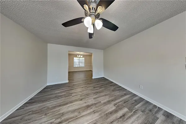 a view of an empty room with window and wooden floor