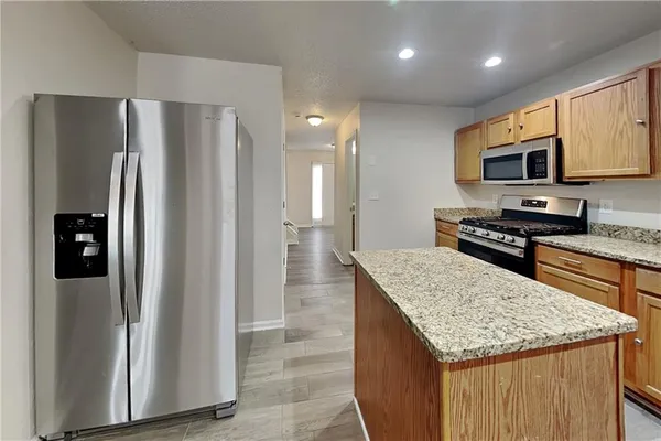 a kitchen with stainless steel appliances granite countertop a refrigerator a stove and a sink