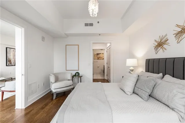 a spacious bedroom with a bed a couch and chandelier