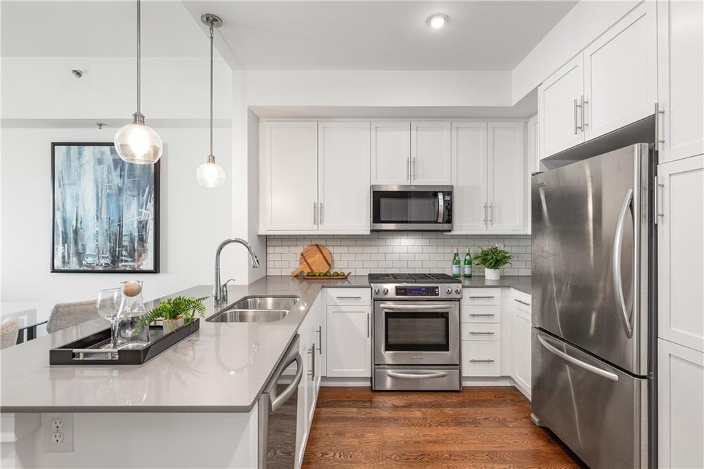1100 Howell Mill Road Northwest, Unit 404 Atlanta, GA 30318 - Photo 6 of 45 a kitchen with stainless steel appliances a refrigerator sink and white cabinets