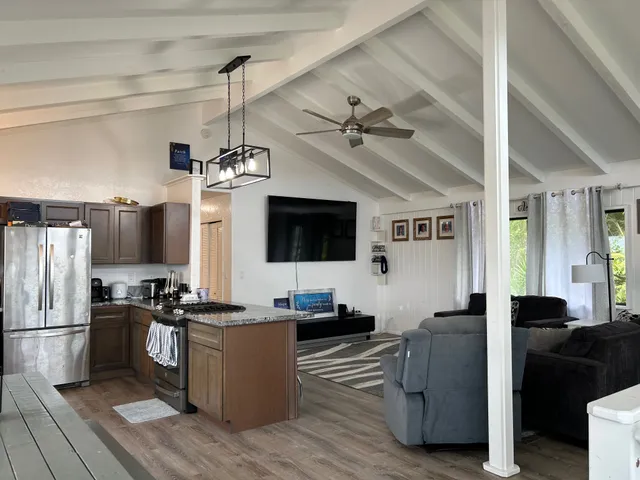 a kitchen with stainless steel appliances kitchen island granite countertop a refrigerator a stove a sink dishwasher a dining table and chairs with wooden floor