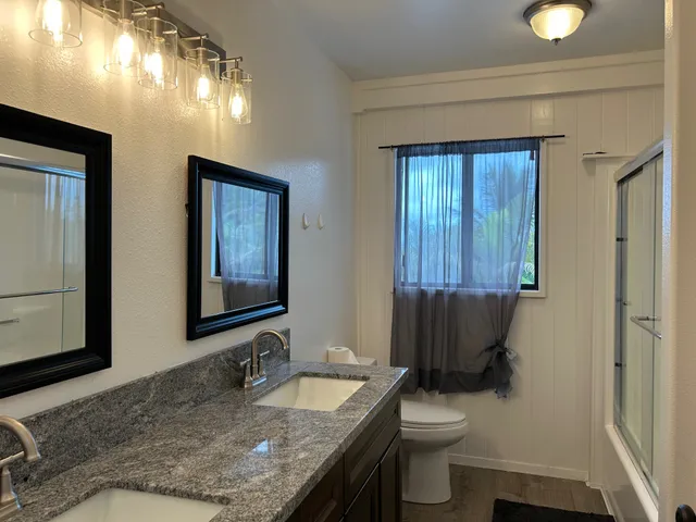 a bathroom with a granite countertop sink and a toilet
