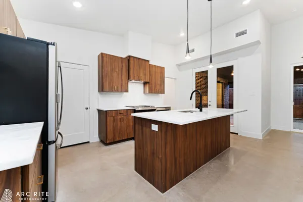 a kitchen with stainless steel appliances granite countertop a wooden cabinets a sink and a refrigerator