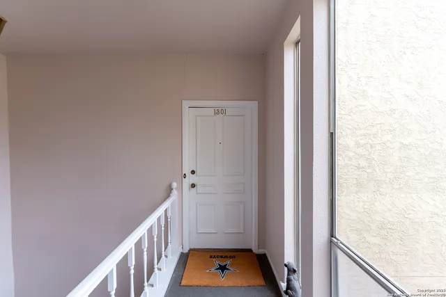 a view of a hallway with white walls and wooden floor