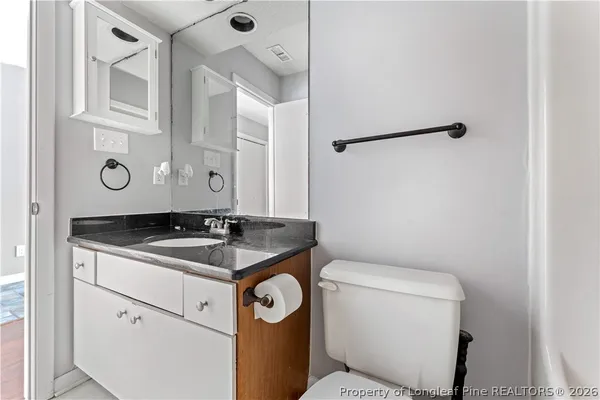 a bathroom with a granite countertop sink and a toilet