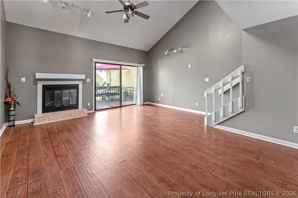 an empty room with wooden floor fireplace and windows