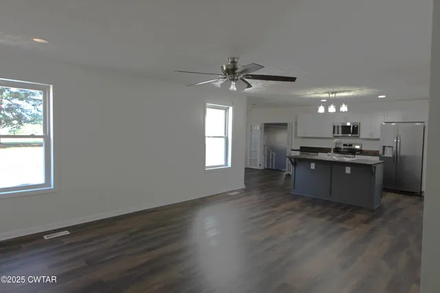 a large kitchen with stainless steel appliances granite countertop a stove a sink dishwasher and a large window with wooden floor