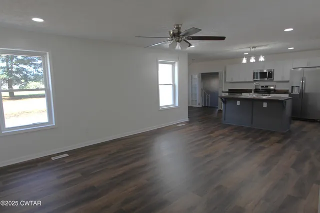 a living room with stainless steel appliances kitchen island hardwood floor and a window