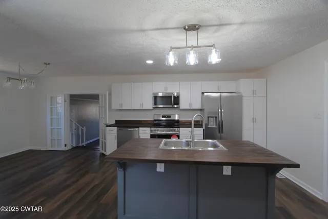 a kitchen with stainless steel appliances a dining table chairs refrigerator and microwave