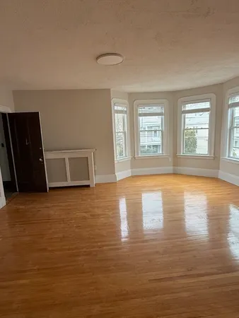 a view of empty room with wooden floor and window