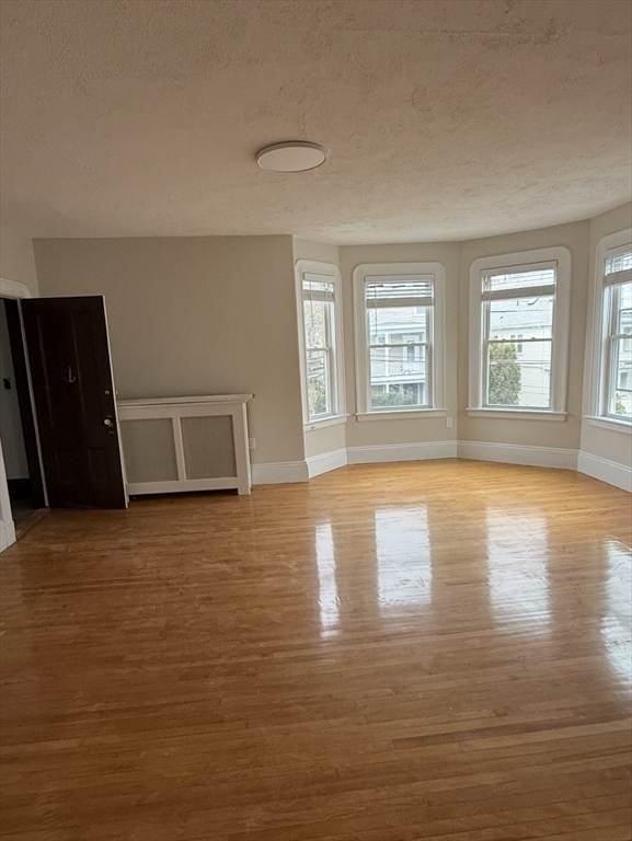98 Paradise Road, Unit 1 Swampscott, MA 01907 - Photo 3 of 10 a view of empty room with wooden floor and window