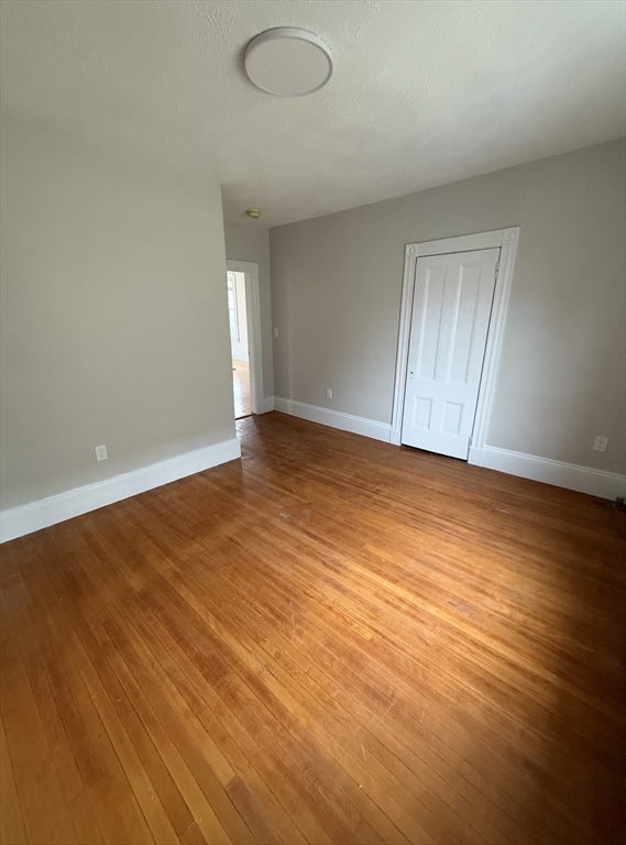 98 Paradise Road, Unit 1 Swampscott, MA 01907 - Photo 5 of 10 an empty room with wooden floor and windows