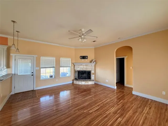 an empty room with windows fireplace and wooden floor