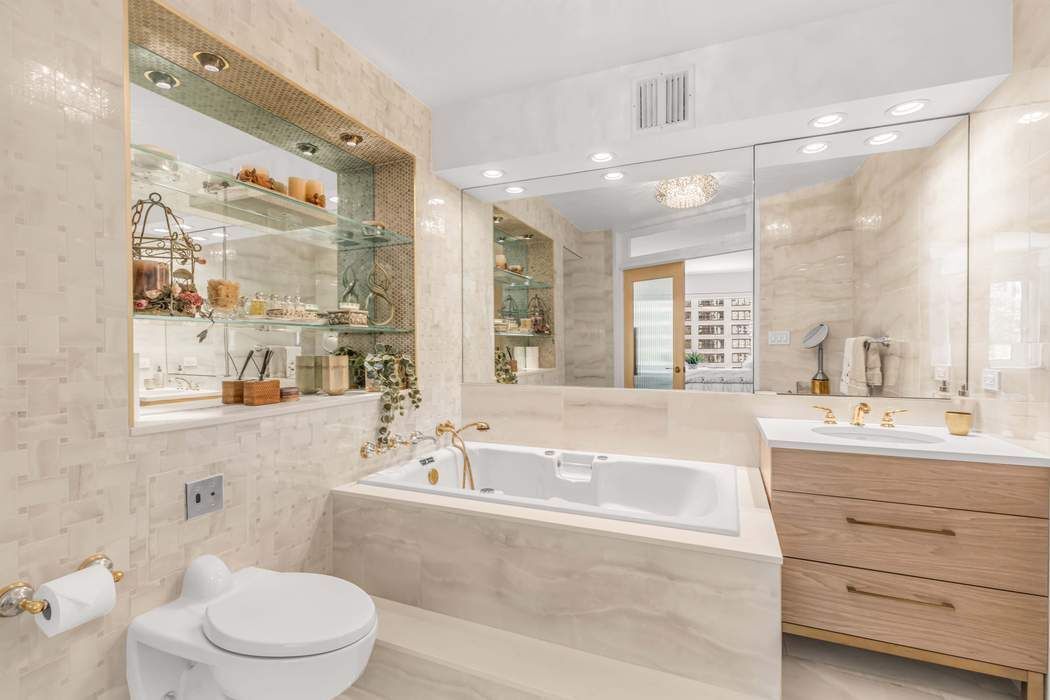 249 East 48th Street, Unit 10B Manhattan, NY 10017 - Photo 9 of 18 a bathroom with a bathtub shower sink mirror vanity and toilet