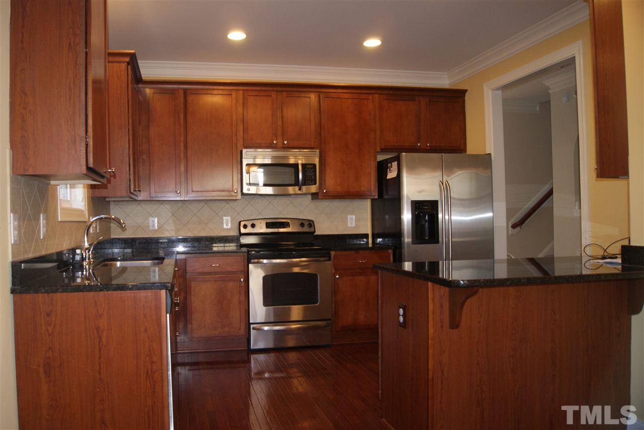 642 Democracy Street Raleigh, NC 27603 - Photo 10 of 25 a kitchen with stainless steel appliances granite countertop a refrigerator a stove a sink and a microwave