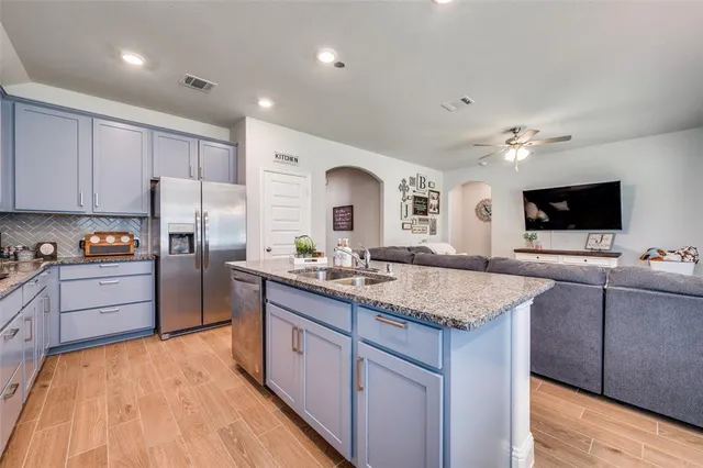 a kitchen with kitchen island granite countertop a stove and a wooden floors