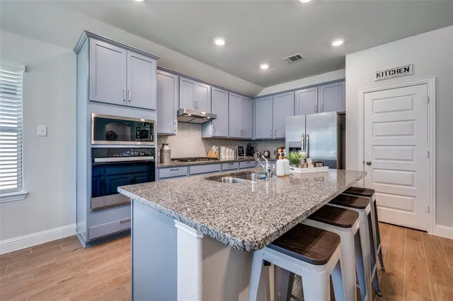 a kitchen with granite countertop a sink stove and refrigerator