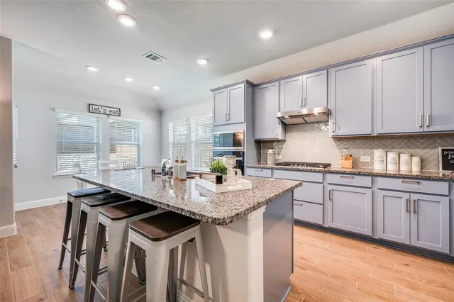 a kitchen with kitchen island granite countertop a sink and white cabinets