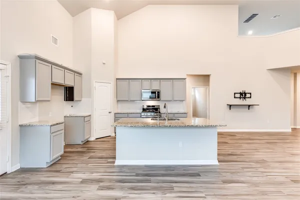 a large white kitchen with kitchen island a sink a stove a refrigerator and white cabinets