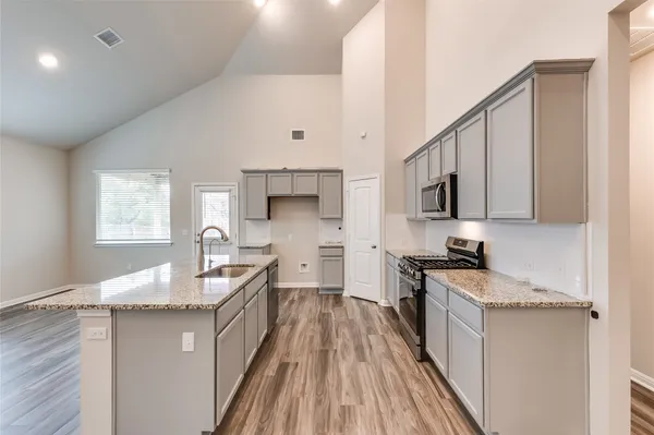 a kitchen with stainless steel appliances granite countertop a sink stove and wooden cabinets