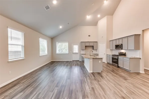 a large kitchen with stainless steel appliances a large counter top a stove and a window