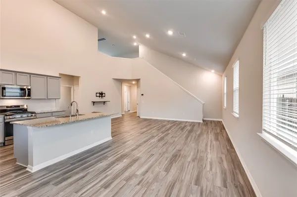 a view of kitchen with cabinets stainless steel appliances and wooden floor