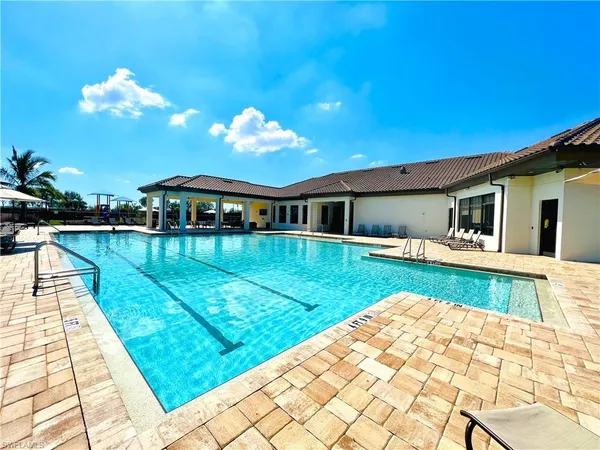 a view of swimming pool with a lounge chair and palm trees