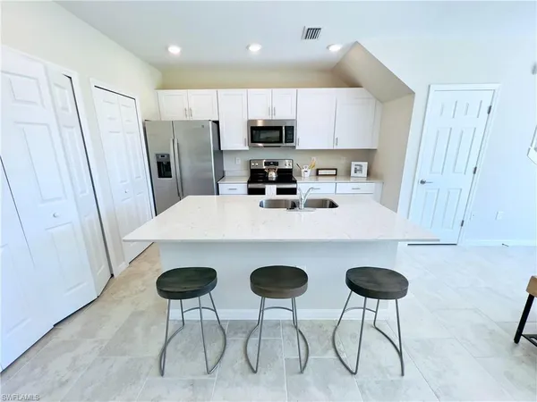 a kitchen with stainless steel appliances granite countertop a sink a stove a refrigerator and white cabinets