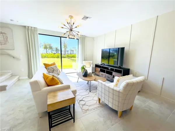 a living room with furniture a flat screen tv and a large window