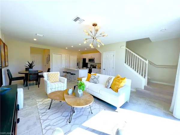 a living room with couches and kitchen view with wooden floor