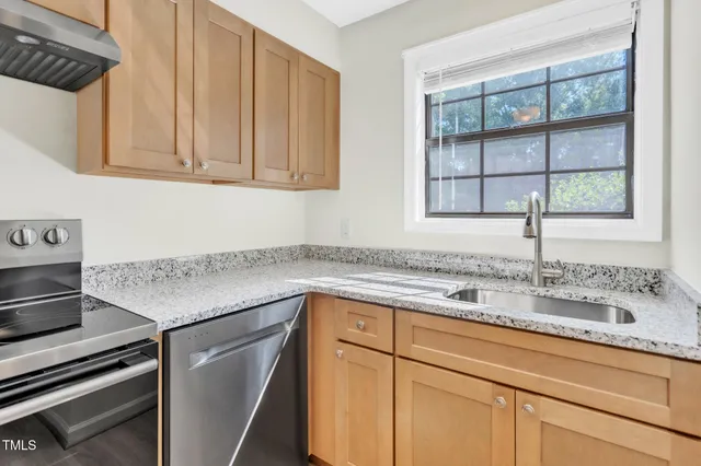 a kitchen with stainless steel appliances granite countertop a sink and a window
