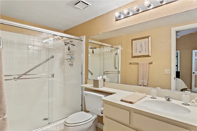 a bathroom with a sink vanity granite toilet and shower